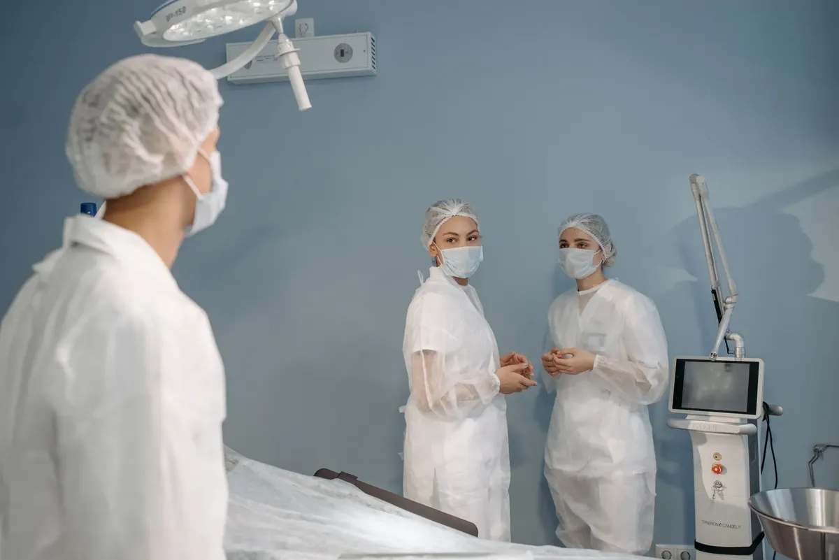 Healthcare professionals in sterile attire conversing in a modern operating room.